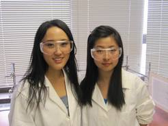 2 female students wearing lab coats and goggles