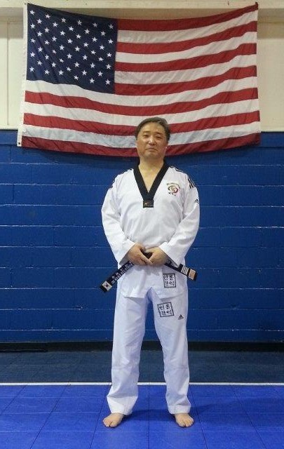 male wearing Taekwondo attire with American flag behind him