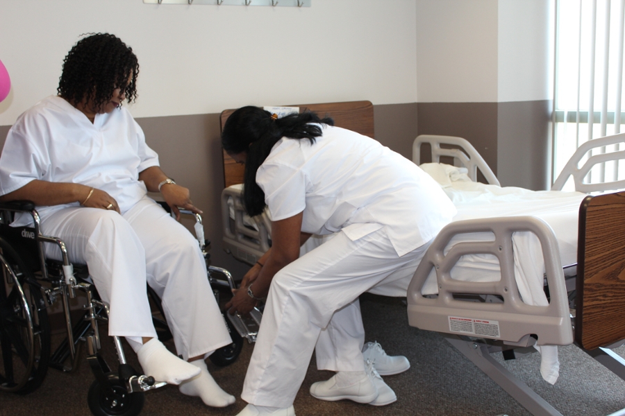 Health Aide student training on assisting a patient in a wheelchair