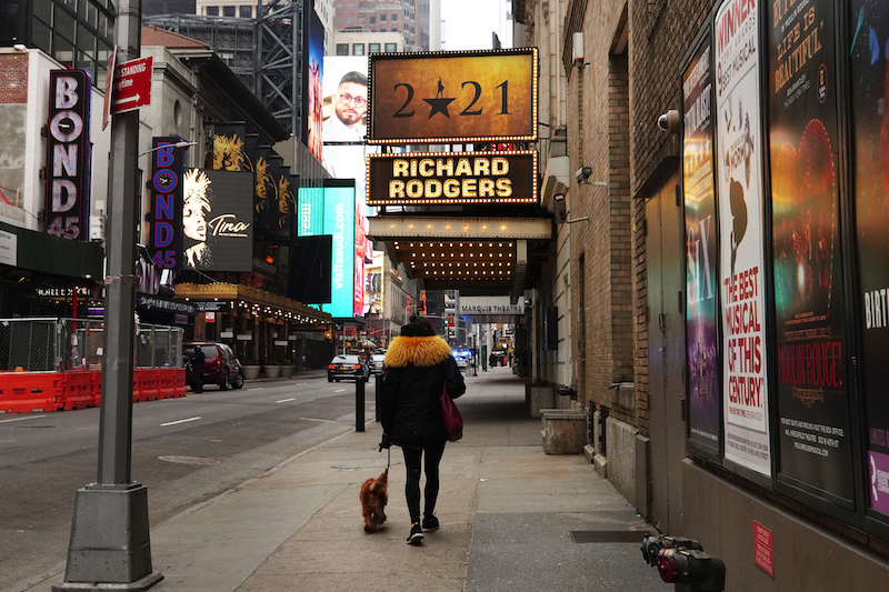 A woman walks by shuttered Broadway theaters. The curtains will be raised again in September.
