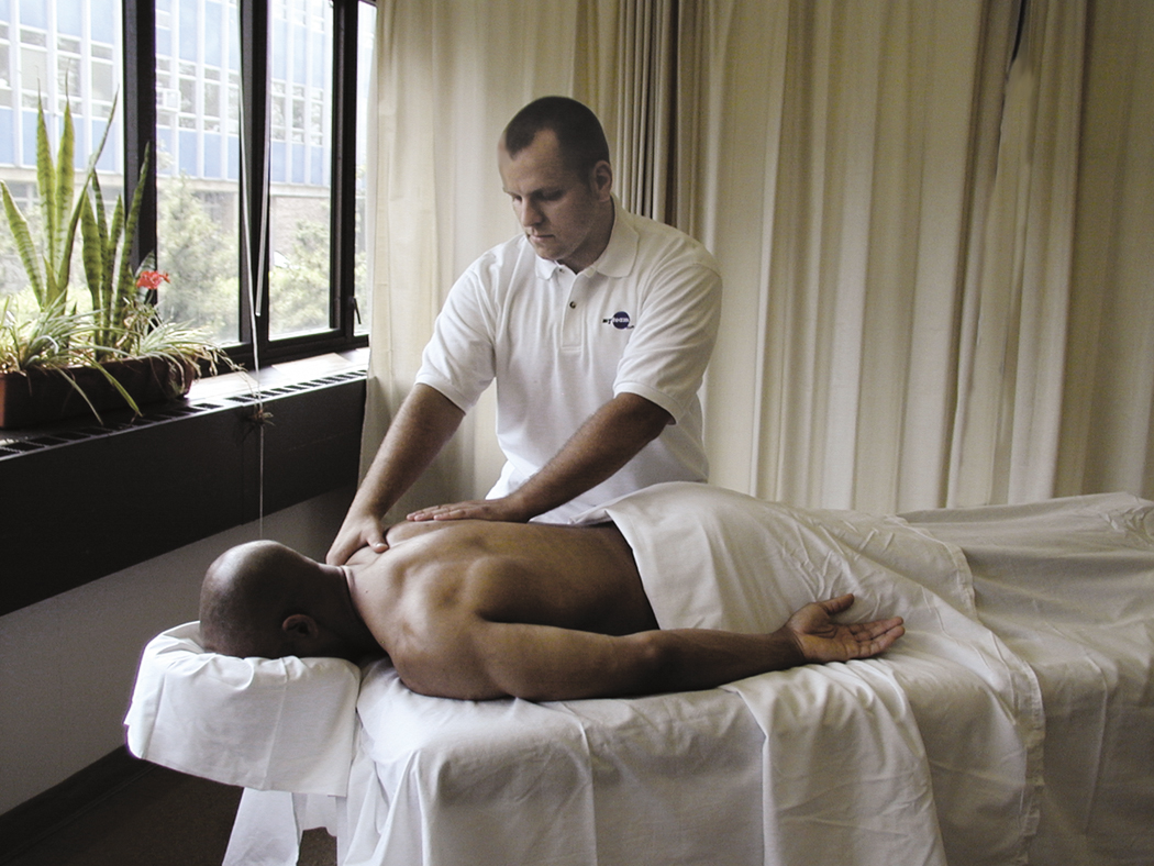 Male massage therapist massages clientes shoulder