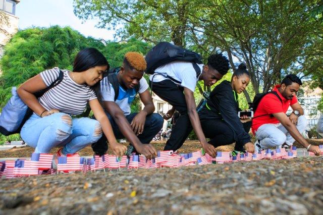 Students place flags on the grounds of Queensborough Community College.