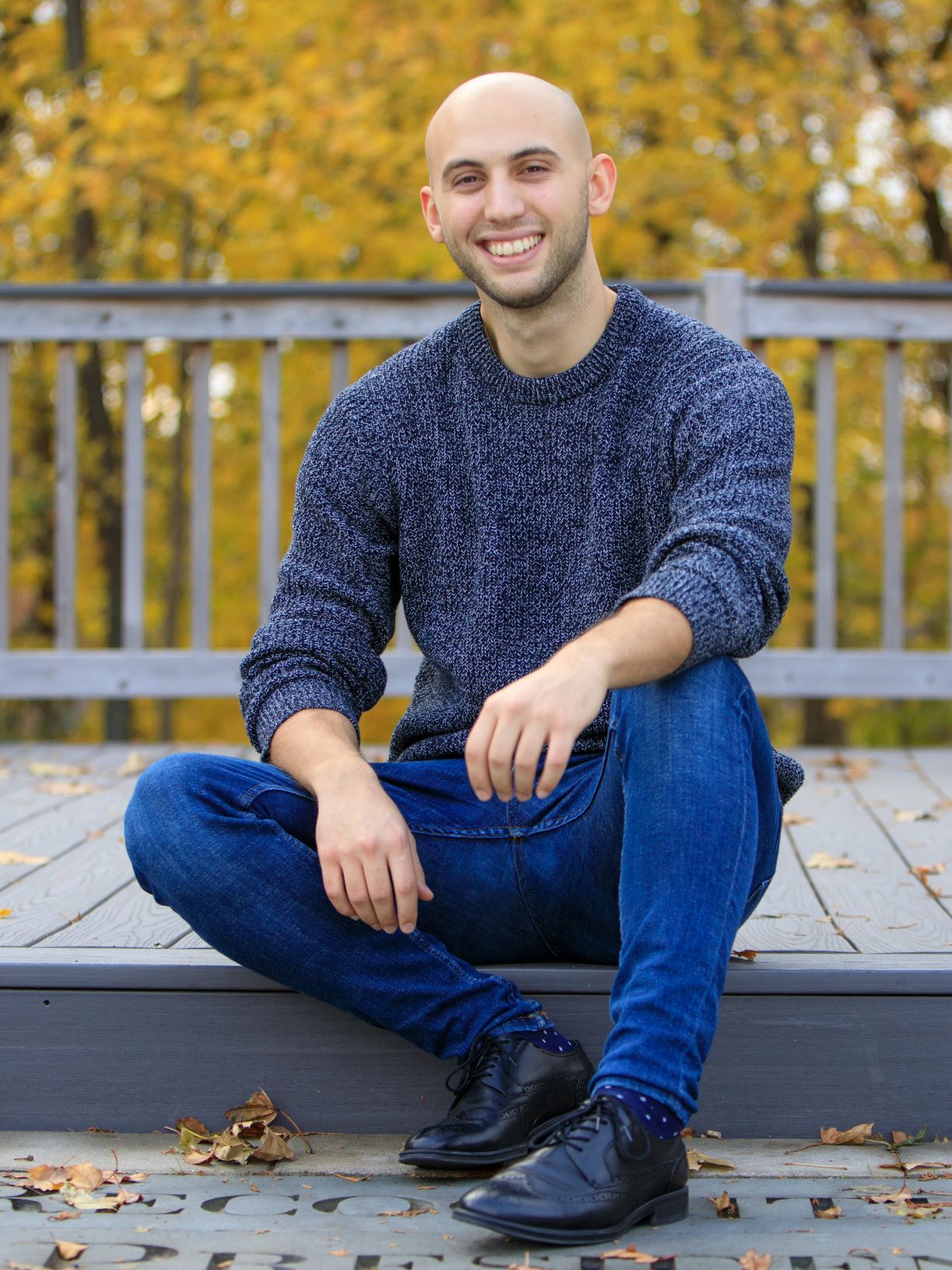 Nikola Baci sitting on a step smiling during Autumn 