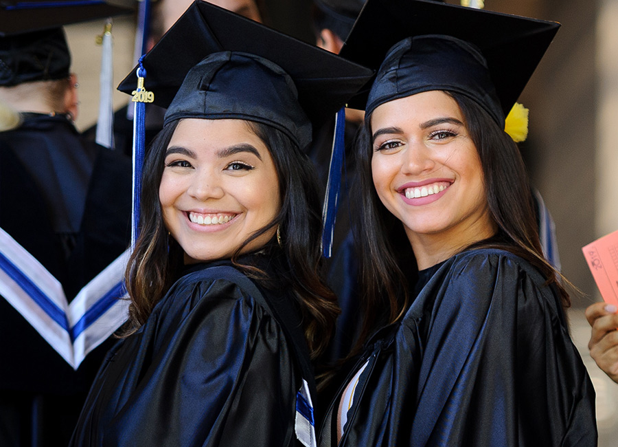two female students wearing graduation cap and gown